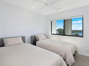 twee bedden in een witte kamer met een raam bij Foreshore Bradman in Diddillibah +4 foto's