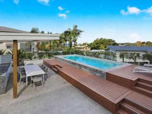 een zwembad met een terras en een tafel en stoelen bij Foreshore Bradman in Diddillibah