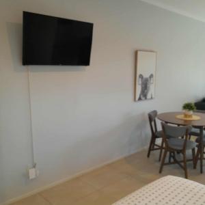 a living room with a table and a television on a wall at Reid's Retreat - Studio Apartment in Port Douglas
