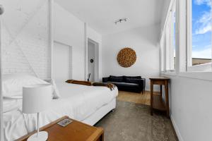 um quarto branco com uma cama e um sofá em Bespoke Stays - Rustic Stanley Bay Apartment em Auckland