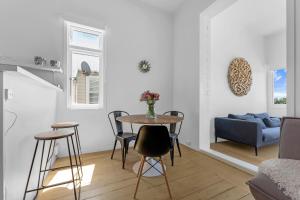 uma sala de estar com uma mesa, cadeiras e um sofá em Bespoke Stays - Rustic Stanley Bay Apartment em Auckland