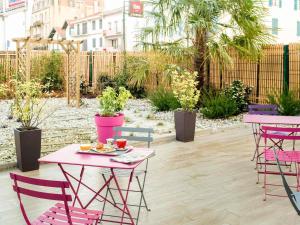 a patio with pink tables and chairs and plants at ibis Bayonne Centre in Bayonne