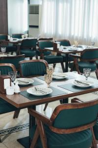 mesas y sillas con platos y vasos encima. en Vogue hotel, en Almaty