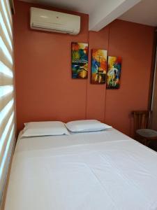 a bed in a room with three paintings on the wall at Villa Anto in Encarnación