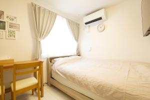 a bedroom with a bed and a desk and a window at オーブリオン恵比寿203 in Tokyo