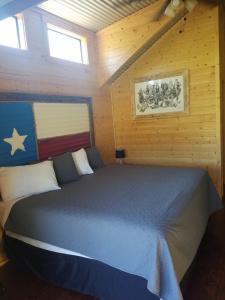 a bedroom with a blue bed in a cabin at Log Cabin for Family Glamping Vacation near San Antonio in Pipe Creek