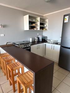 a kitchen with a black counter top and a refrigerator at Acogedor y amplio, cercano al Hospital de Ovalle in Ovalle