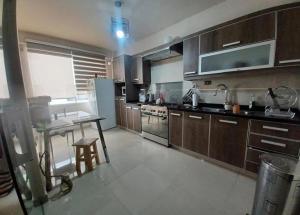a kitchen with wooden cabinets and a table in it at los hirukus cusco in Cusco