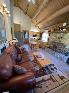 sala de estar con sofá de cuero y chimenea de piedra en Montana Mountain Glamping: Charming Log Cabin with a Private Hot Tub in Darby, en Peaks and Pines Park