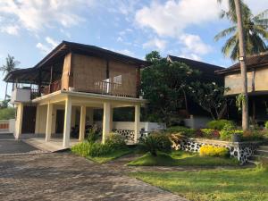 a house with a palm tree in front of it at Villa RR Senggigi in Senggigi