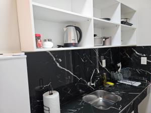 a kitchen with white cabinets and a black counter top at Easy Access Apartment - Ciudad del Este in Ciudad del Este +54 photos