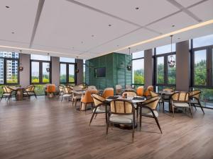 a dining room with tables and chairs and windows at Holiday Inn Beijing Daxing Centre by IHG in Beijing