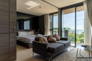 a bedroom with a bed and a couch and a balcony at Seaphere Residence by Prop Hopper in Na Jomtien