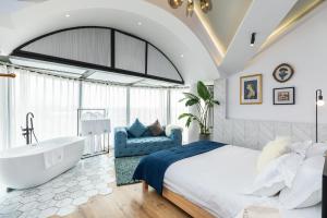 a bedroom with a tub and a bed and a couch at Shanghai Yipin Yijing B&B - Disney 上海一品艺景民宿-迪士尼店-近浦东国际机场 in Shanghai