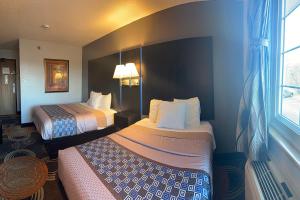 a hotel room with two beds and a window at Coratel Inn and Suites by Jasper Stillwater in Stillwater