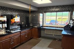a kitchen with wooden cabinets and a window at Coratel Inn and Suites by Jasper Stillwater in Stillwater