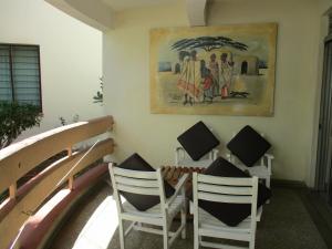 a dining room with white chairs and a painting on the wall at Indiana Beach Apartments in Bamburi