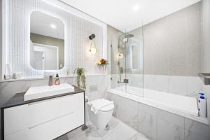 ein weißes Badezimmer mit einer Badewanne, einem WC und einem Waschbecken in der Unterkunft Modern 2Bed 2bath 1 multipurpose room apartment 350m to Kogarah Station 15min train to airport in Sydney + 10 Fotos