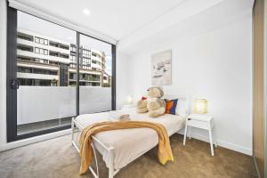 ein Teddybär sitzt auf einem Bett in einem Schlafzimmer in der Unterkunft Modern 2Bed 2bath 1 multipurpose room apartment 350m to Kogarah Station 15min train to airport in Sydney
