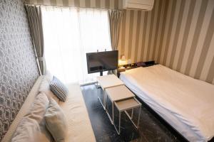 a hotel room with a bed and a tv at Guesthouse Life Field in Kurashiki