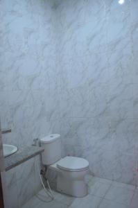 a white bathroom with a toilet and a sink at Villa Omah Jamuniro in Ngasinan