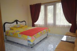 a bedroom with a bed with red curtains and windows at Villa Omah Jamuniro in Ngasinan +8 photos