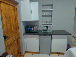 a kitchen with white cabinets and a black counter top at WegkruiperQ in Beaufort West