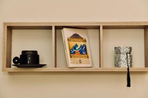 a shelf with a coffee mug and a book at Four Stays Khobar in Al Khobar