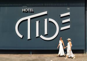 two women walking in front of a hotel sign at Hotel Tide Phuket Beachfront in Phuket Town