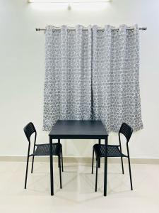 a black table and two chairs in front of a curtain at 1 BHK Near AIG Hospital Sai Castle Serviced Apartment in Kondapur