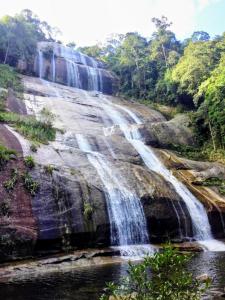 een waterval aan de zijkant van een berg met bomen bij Flat Aconchegante e Tranquilo in Campos dos Goytacazes