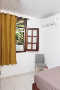 a bedroom with a bed and a chair and a window at Kaz mahury zen-wifi-climatisation in Rémiré