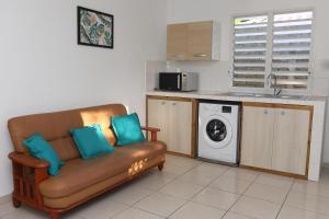 a living room with a couch and a washing machine at Kaz mahury zen-wifi-climatisation in Rémiré