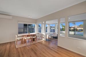 a dining room with a table and chairs and windows at Casa Esperanza by Experience Jervis Bay in Vincentia