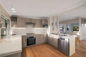a large kitchen with white cabinets and stainless steel appliances at Casa Esperanza by Experience Jervis Bay in Vincentia