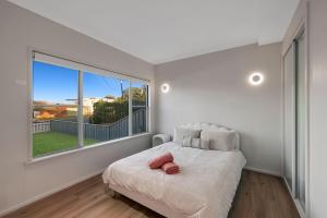 a white bedroom with a bed and a large window at Casa Esperanza by Experience Jervis Bay in Vincentia