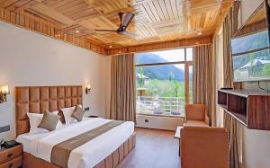 een slaapkamer met een groot bed en een groot raam bij Omavya Hotel Manali in Jagatsukh