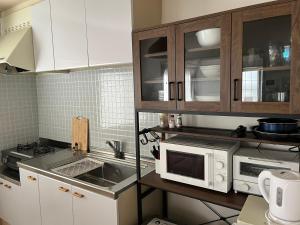 a kitchen with white cabinets and a sink and a microwave at 江の島HOUSE Comfortable & Relaxing Stay in Fujisawa