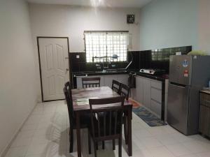 a kitchen with a table and chairs and a refrigerator at Teratak Desa Cemerlang 1 in Enggur