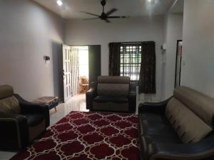 een woonkamer met een bank en een stoel bij Teratak Desa Cemerlang 1  +1 foto