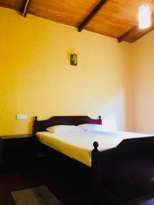 a bed in a room with a yellow wall at Gam Maduwa , cooking class and Tours in Nuwara Eliya