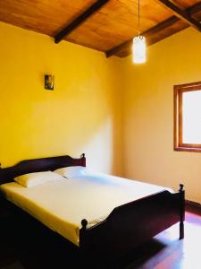 a large bed in a room with yellow walls at Gam Maduwa , cooking class and Tours in Nuwara Eliya