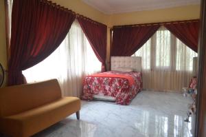 a room with a bed and a couch and windows at Villa Omah Jamuniro in Ngasinan