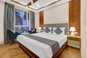 a bedroom with a bed and a desk and a window at Hotel Aerotech Near Delhi Airport in New Delhi