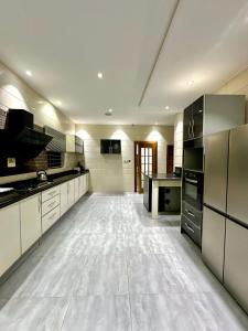 une grande cuisine avec des sols blancs et des appareils électroménagers noirs dans l'établissement Mega Villa 5 Bedroom Stand Alone Duplex, à Ikuata