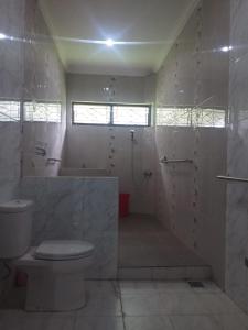 a white bathroom with a toilet and a shower at Villa Omah Jamuniro in Ngasinan