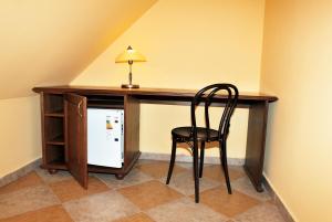 einen Stuhl neben einem Schreibtisch mit einem Kühlschrank in der Unterkunft Hotel Pelikán in Třeboň