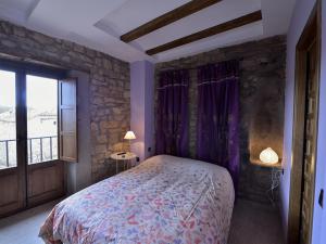 1 dormitorio con cama y pared de piedra en Ana de las Tejas Azules, en Medinaceli