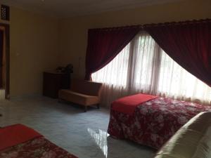 a bedroom with a bed and a window with a chair at Villa Omah Jamuniro in Ngasinan