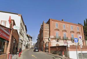 une rue de la ville avec des bâtiments et une voiture sur la route dans l'établissement La cinemaRoom d'Auterive - Son Immersif Dolby et Atmos - Netflix, à Auterive